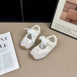 Top-down detail of cream children's Mary Jane sneakers featuring elegant lace ribbons