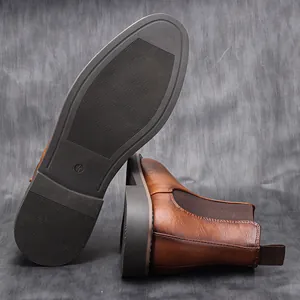 Detail view of men's brown Chelsea boot side profile and textured non-slip rubber sole.