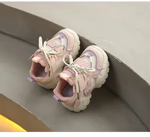 Close-up detail of stylish pink and purple children's chunky sneakers on grey stone stairs