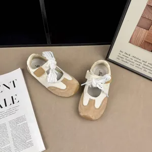 Detail of cream and tan children's sneakers with lace ribbons on a fashion background