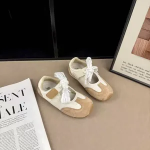 Macro view of stylish cream and tan children sneakers featuring elegant lace ties and mesh fabric.