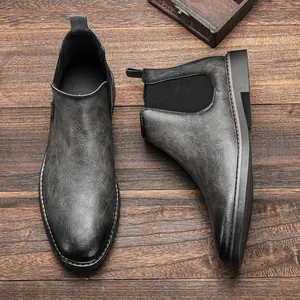 Detailed top view of vintage distressed gray men's Chelsea boots on wooden surface