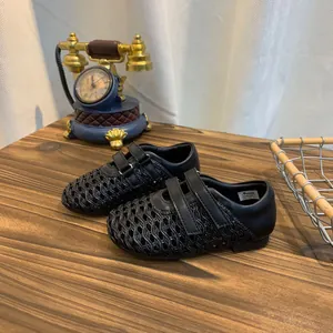 Close-up of black hollow-out woven Mary Jane shoes with velcro strap on wooden table