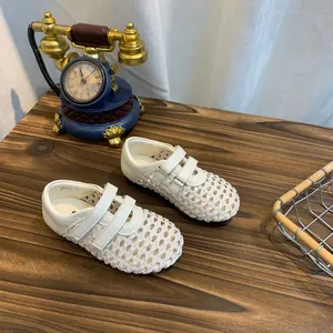 Close-up detail of white woven hollow-out Mary Jane flats with adjustable velcro straps