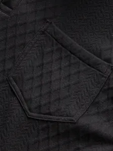 Détail macro de la texture du tissu jacquard noir sur une poche de T-shirt homme