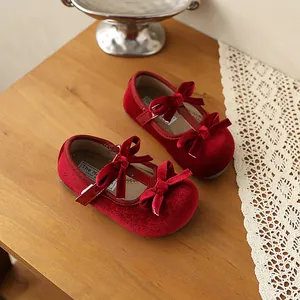 Vista detallada de zapatos de terciopelo rojo para bebé con elegantes lazos dobles