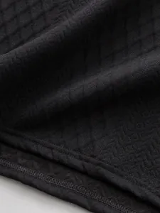 Vue macro rapprochée de la texture du tissu jacquard noir et des coutures de l'ourlet