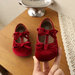 Primer plano de hermosos zapatos de bebé en terciopelo rojo con lazos elegantes.