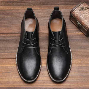 Vue de dessus de bottines désert en cuir noir pour hommes sur fond en bois vintage