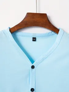 Détail du col d'un t-shirt Henley bleu clair avec boutons noirs et étiquette de taille M