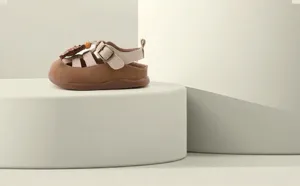 Detailed view of baby girl's brown cartoon Roman sandals on a platform