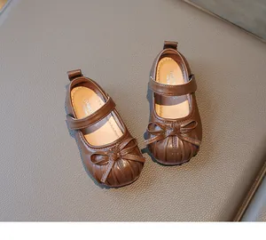 Close-up detail of toddler girls brown Mary Jane leather shoes with bow decoration
