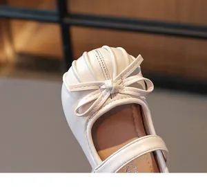 Close-up detail of cream children's Mary Jane shoe featuring a delicate bow on the toe