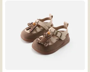 Detailed macro shot of toddler baby girl Roman sandals featuring a cute brown bear design