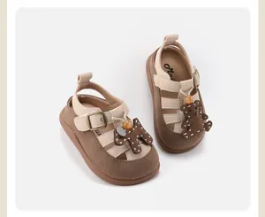 Detailed view of beige baby girl Roman sandals featuring cute cartoon bear accents
