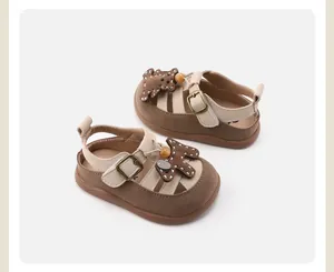 Detailed view of brown and cream baby sandals with a cute cartoon teddy bear motif