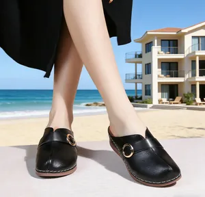 Detail of black perforated leather wedge mules with gold buckle and white stitching