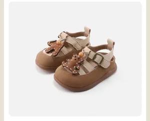 Close-up of baby soft-sole sandals with a cute brown cartoon bear and beige straps