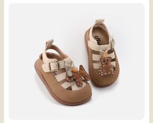 Close-up of baby girl's brown Roman sandals with cute cartoon bear and puppy decorations.