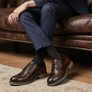 Primo piano di scarpe stringate in pelle marrone vintage indossate su un divano in pelle