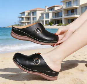 Detailed view of women's black closed-toe clogs with wedge soles on a sunny beach