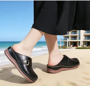 Close-up detail of stylish black leather closed-toe wedge sandals for women on a sunny beach
