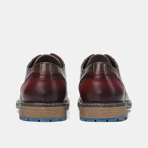 Rear view of vintage brown and burgundy leather dress shoes with thick blue soles.