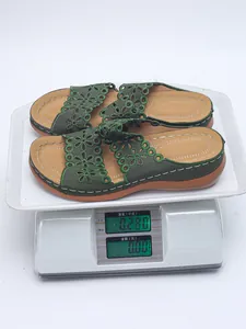 Nahaufnahme grüner Plateausandalen mit Blumen, Gewicht 0,28 kg auf einer digitalen Waage