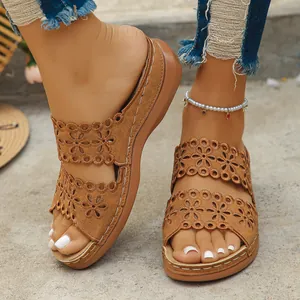Detailansicht brauner Keilsandalen mit lasergeschnittenem Blumenmuster auf den Riemen