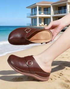 Close-up of dark brown wedge sandals featuring a decorative metal ring on a sunny beach.