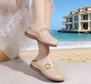 Comfortable beige hollowed-out mules for women with wedge soles on a beach setting