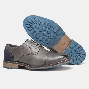 Dettaglio di scarpe stringate grigie da uomo con suola in gomma blu testurizzata.