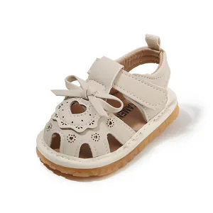 Beige baby girl summer sandals with bow and heart cutout details and soft sole.