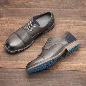 Dettaglio di scarpe stringate grigie da uomo con trama in pelle e suola in gomma blu.