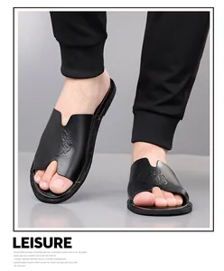 Detailweergave van de zwarte lederen heren slippers met een reliëf van een leeuwenkop