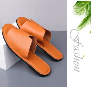 Gedetailleerde weergave van oranje leren herenslippers met reliëf van een leeuwenkop