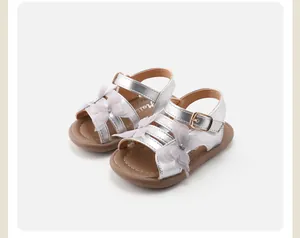 Close-up of silver baby girl sandals with delicate white lace butterfly decorations