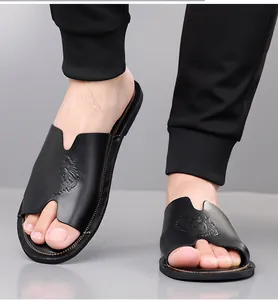 Close-up van zwarte heren slippers met een reliëf leeuwenkop op de voeten.