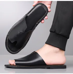 Gedetailleerd beeld van zwarte leren herensandalen met reliëflogo en zachte zool.