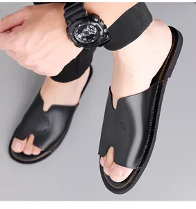 Detailopname van zwarte herenslippers met reliëf leeuwenkop en V-vormige uitsnede