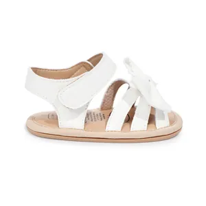 Vue latérale détaillée de sandale blanche brillante pour bébé fille avec nœud et velcro