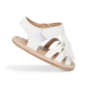 Détail de sandales blanches brillantes pour bébé fille avec un nœud et une bride velcro
