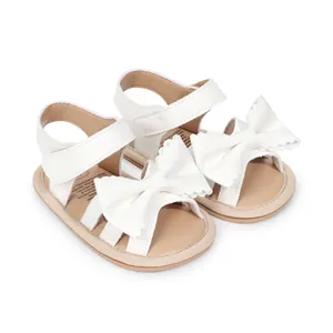 Détail de sandales blanches brillantes pour bébé avec nœuds décoratifs et semelles souples
