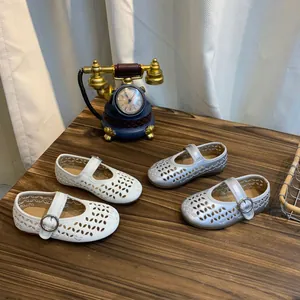 Close-up van witte en zilveren opengewerkte Mary Jane-schoenen voor meisjes.