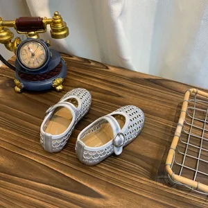 Detailweergave van zilveren Franse Mary Jane schoenen voor meisjes op houten tafel.
