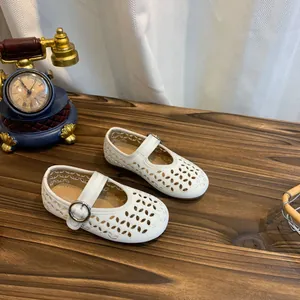 Gedetailleerd overzicht van witte Franse Mary Jane-schoenen met gaten voor meisjes op hout