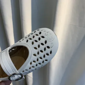 Detailopname van elegante witte geborduurde uitsnijdingen op meisjes Mary Jane schoenen