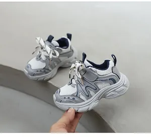 Gros plan de baskets épaisses pour enfants, grises et blanches, avec bandes velcro.