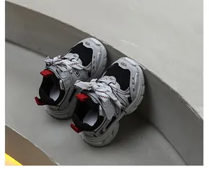 Vue détaillée de dessus de baskets en maille pour enfants grises et noires sur un escalier