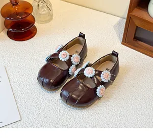 Detailed macro view of girls' burgundy Mary Jane shoes with decorative floral straps